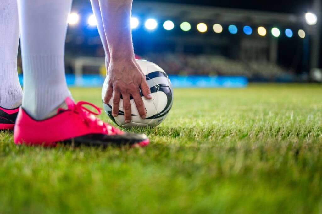 Soccer player placing ball right before a free kick wearing his soccer leats