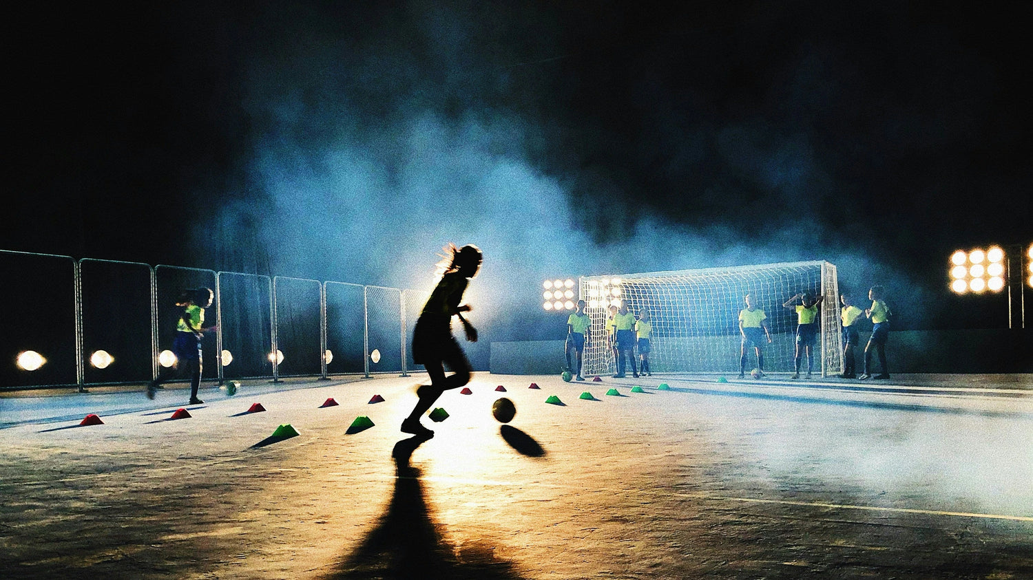 Young soccer players training on a field at night time
