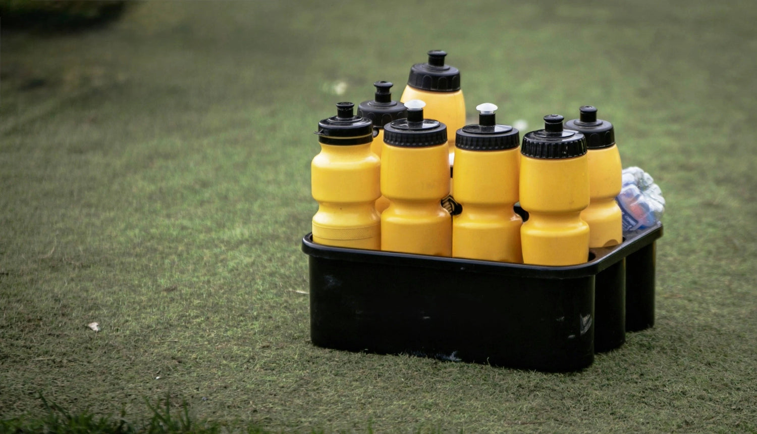 Yellow water bottles in a pack on a green soccer field