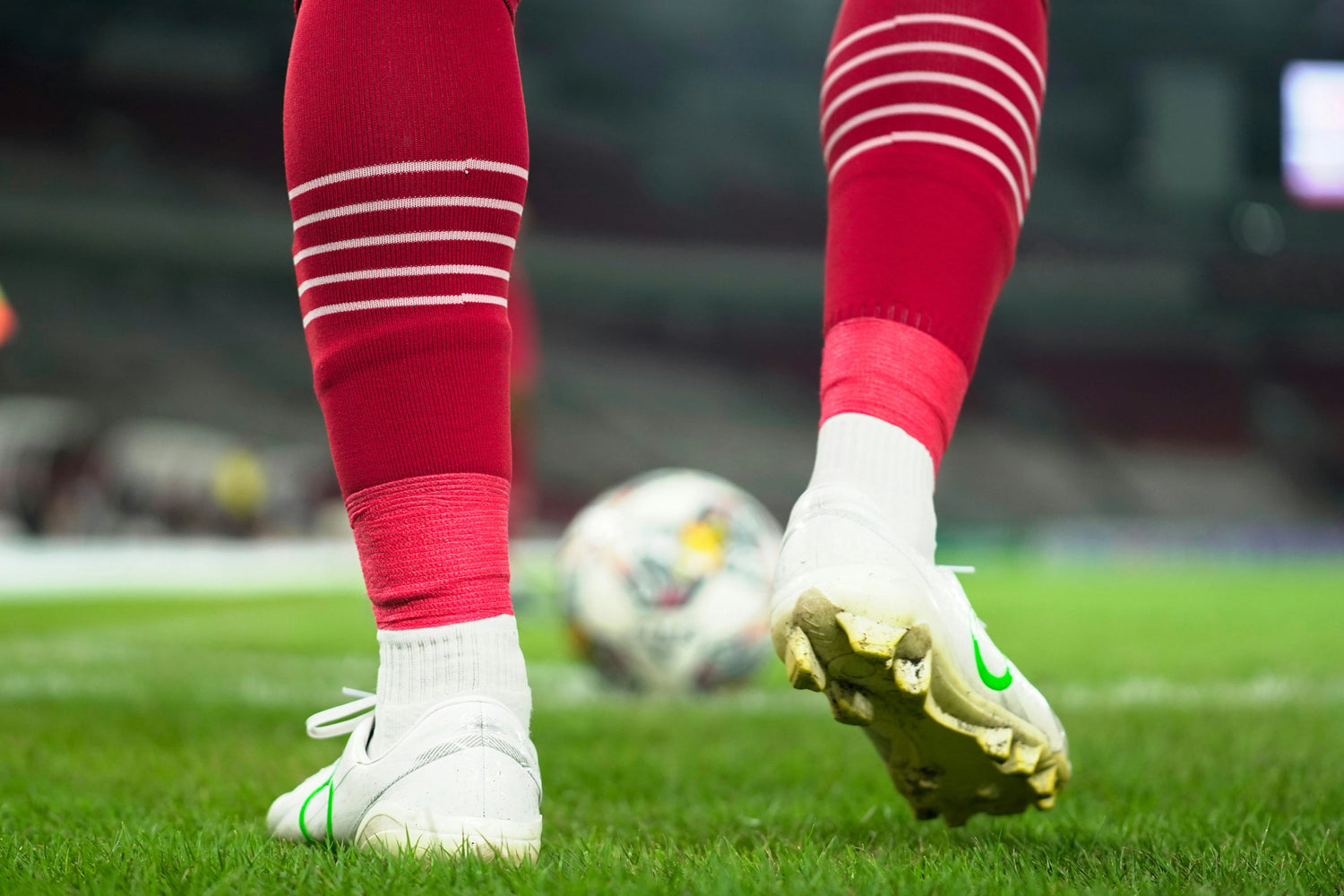 Red soccer socks on a soccer player as he approaches the ball